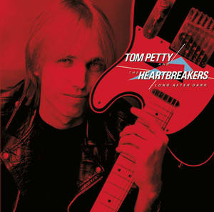 Tom Petty 在紅色背景上手持紅色電吉他，並有專輯文字。 — 黑夜 壁紙