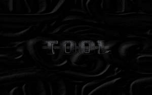 在黑暗漣漪布料背景上顯示「TOOL」的金屬文字。 — 工具 壁紙