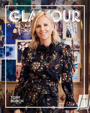 Tory Burch 身穿花卉連衣裙，在拼貼背景的 Glamour 雜誌封面上微笑。 — 4:5 壁紙