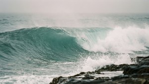 一道巨大的海浪帶著白色泡沫衝擊岩石海岸。
