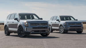 兩輛灰色Kia Telluride SUV停泊在靠近海洋的沿海道路上。 — 起亞 壁紙