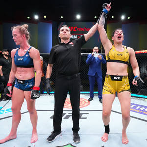 UFC拳手贏得比賽，裁判舉起她的手宣告勝利。 — 1:1 壁紙