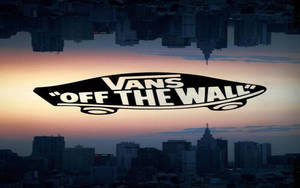 Vans Off The Wall 標誌漂浮在日落時分的城市上空，帶有水倒影。 — 墜落卡車 壁紙
