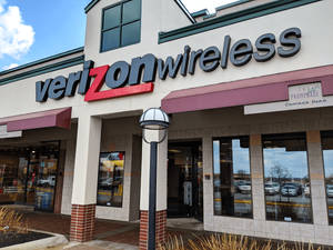 Verizon Wireless 店面外觀，在藍天下設有紅色和灰色招牌及磚柱。 — 威訊 壁紙