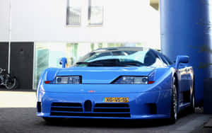 藍色Bugatti EB110超級跑車停泊在現代建築附近的人行道上。 — Steam Deck OLED 壁紙
