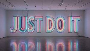 現代藝術畫廊中，一個大型彩色霓虹招牌寫著 JUST DO IT。