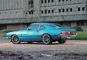 綠松石色經典肌肉車停在塗鴉覆蓋的工業建築前。 — 福特 壁紙