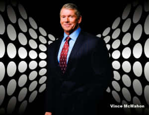 Vince McMahon 身穿深色西裝和紅色領帶，站在帶有白色橢圓燈光的黑色牆壁前。 — WWE GIF 壁紙