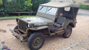 橄欖綠軍用吉普車，帶帆布頂篷，停在碎石上，靠近綠植。 — 吉普 壁紙