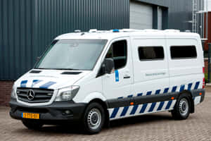 白色荷蘭警車帶藍色條紋停在磚砌路面。 — Mercedes Benz C300 壁紙