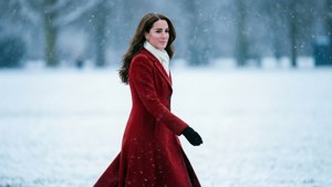 冬季降雪時，身穿紅色外套的女性在雪地中行走。