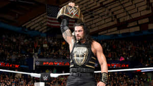 摔角手Roman Reigns在歡呼的人群前於場館中高舉WWE冠軍腰帶。 — WWE GIF 壁紙