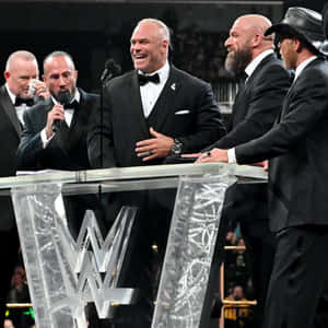 WWE摔角手穿著禮服在正式活動中在講台上笑。 — 摔角 壁紙