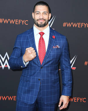 Roman Reigns在WWE活動中身穿藍色格紋西裝和紅色領帶。 — 羅曼·雷恩斯 壁紙