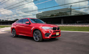 陽光明媚的日子，紅色BMW X6 M停在玻璃建築前方。 — Steam Deck 壁紙