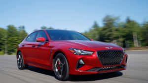 紅色現代 Genesis 轎車在陽光明媚、綠樹成蔭的道路上行駛。 — 創世紀 壁紙
