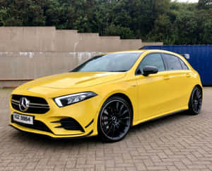 黃色Mercedes-AMG A45 S停放在混凝土牆和樹木附近的鋪砌表面。 — Mercedes-Benz 壁紙