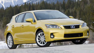 黃色Lexus CT 200h混合動力車停在碎石路上，靠近雪山和森林。 — 凌志 壁紙