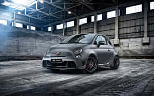 消光灰色的Fiat 500 Abarth跑車在一個工業倉庫中，地板是混凝土的，天花板很高。 — Steam Deck OLED 壁紙
