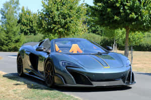 消光灰色McLaren跑車配橙色座椅，停泊在陽光道路旁近樹木。 — Surface Laptop 壁紙