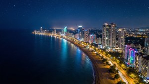 夜間沿海城市，建築物閃爍，星空璀璨