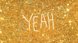 「yeah」這個字以白色寫在金色閃粉背景上。