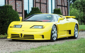 黃色Bugatti EB110超級跑車停放在磚造建築附近的碎石地上。 — MacBook Pro 13 壁紙