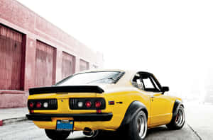 黃色經典馬自達RX-7跑車停在磚砌倉庫旁。 — 馬自達 壁紙