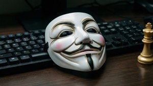 白色蓋伊·福克斯面具在鍵盤上，旁邊是木桌上的金色西洋棋國王。