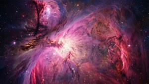 在深空中閃耀著星星的充滿活力的粉紅色、紫色和紅色星雲。