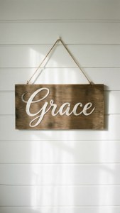 木牌上寫著Grace，掛在白色拼接牆上，陽光投下陰影。