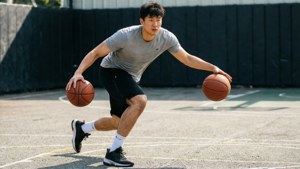 年輕男子在戶外球場上運兩個籃球。