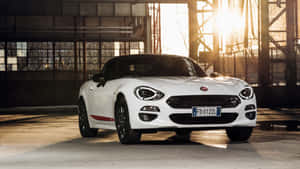 日落時工業倉庫中的白色Fiat 124 Spider敞篷車。 — iMac 壁紙