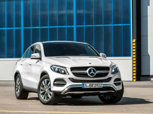 白色 Mercedes GLE Coupe 停放在藍色玻璃建築前。 — Mercedes-Benz 壁紙
