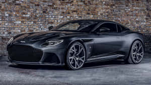啞光黑色 Aston Martin 跑車在車庫磚牆旁。 — 奧斯頓馬丁 壁紙