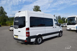 白色 Mercedes-Benz Sprinter 客貨車停放在戶外停車場，有樹木及其他車輛。 — Surface Pro 壁紙