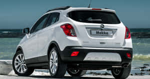 白色Opel Mokka SUV停泊在岩石海灘上，伴有海浪。 — 歐寶 壁紙