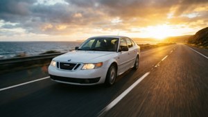白色汽車在金色日落時分於海岸道路疾駛