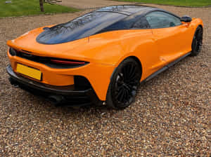 橙色McLaren跑車停在碎石車道上 — 酷炫F1 壁紙