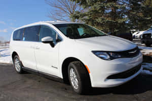 白色 Chrysler Pacifica 小型貨車停泊在雪地上，有樹木和晴朗天空。 — Surface Pro 壁紙