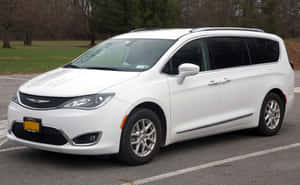 白色 Chrysler Pacifica 小型貨車停放在停車場，後面有樹木和草地。 — MacBook Air M1 壁紙