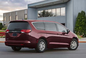 栗色Chrysler Pacifica小型貨車在黃昏時停泊在現代建築前。 — Surface Laptop 壁紙