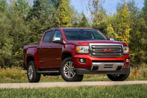 紅色GMC Canyon皮卡車停在有秋天樹木和草的道路上。 — 3:2 壁紙