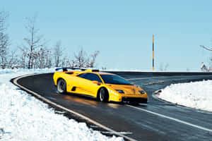 黃色藍寶堅尼 Murciélago 在積雪的山路上飛馳。 — Surface Pro 壁紙