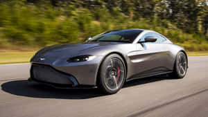銀色Aston Martin Vantage在綠樹成蔭的道路上疾馳。 — 奧斯頓馬丁 壁紙
