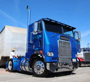 一輛藍色 Freightliner 半掛卡車停在晴朗的天空下，附近有一名工人。 — 老福特卡車 壁紙