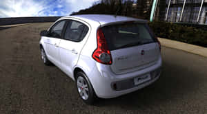 白色Fiat Polo停泊在現代建築附近的彎曲道路上。 — 飛雅特 壁紙