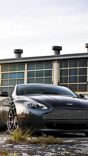 黑色Aston Martin停在工業建築前，地面有雪 — 阿斯頓維拉 壁紙