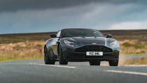 黑色Aston Martin V12 AMR在暴風雲下行駛在鄉村道路上。 — 奧斯頓馬丁 壁紙