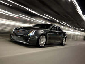 黑色Cadillac CTS-V在夜間隧道中高速行駛，帶有動態模糊效果。 — 凱迪拉克 壁紙